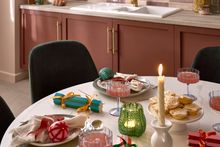 Colourful festive dining table set with plates, glasses, and napkins.
