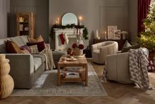Cosy chaise sofa bed and armchairs set with decorative pillows in a warm living room.