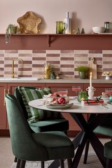 A set of green upholstered dining chairs around a ceramic round table.