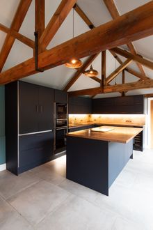 Modern black kitchen cabinets with a wooden countertop.