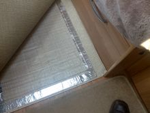 The RugBuddy is shown on its underlay, on the floor, with the covering mat pulled back to top right 