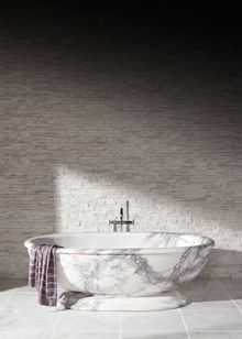 Calacatta Viola Honed Marble Vesta Bath which costs £13,140.00. On the walls is White Quartzite Maxi Splitface which costs £57.4