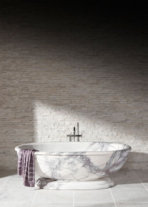 Calacatta Viola Honed Marble Vesta Bath which costs £13,140.00. On the walls is White Quartzite Maxi Splitface which costs £57.4